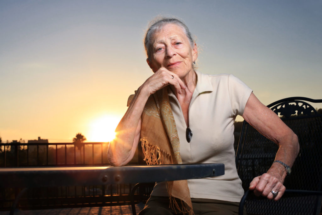 Senior woman sitting at the table outdoors at sunset.